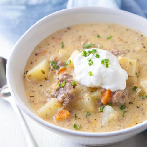 bowl of crockpot cheeseburger soup topped with sour cream and chives.