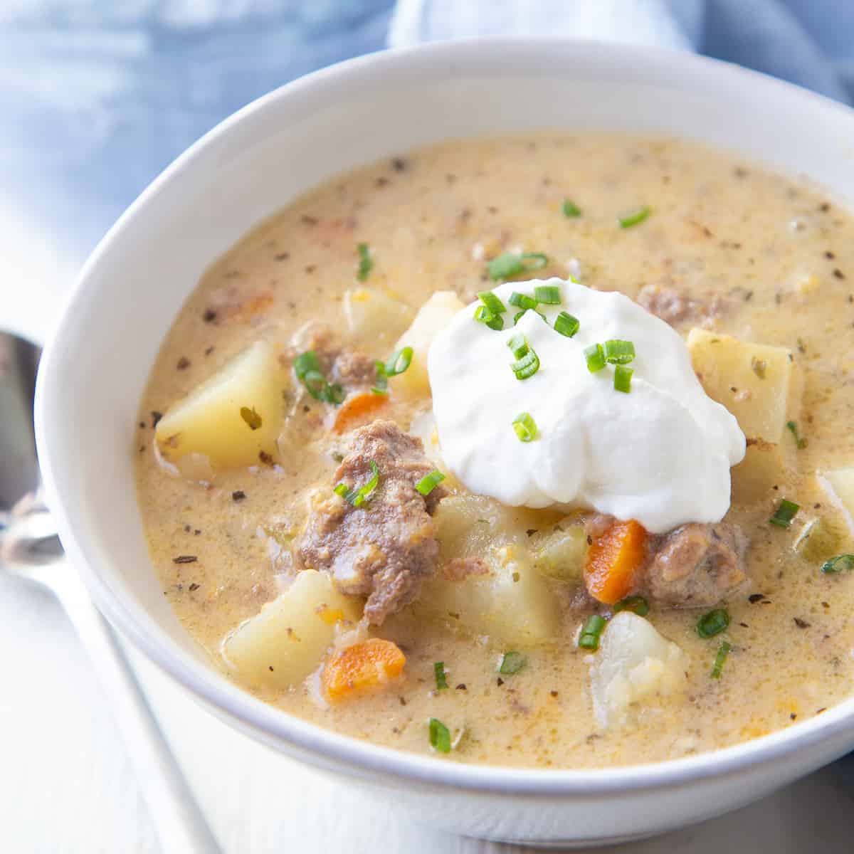 bowl of crockpot cheeseburger soup topped with sour cream and chives.