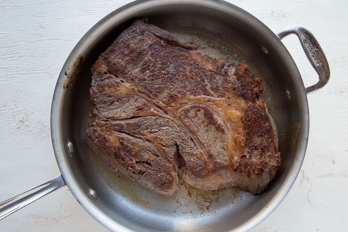 chuck roast in a metal skillet.