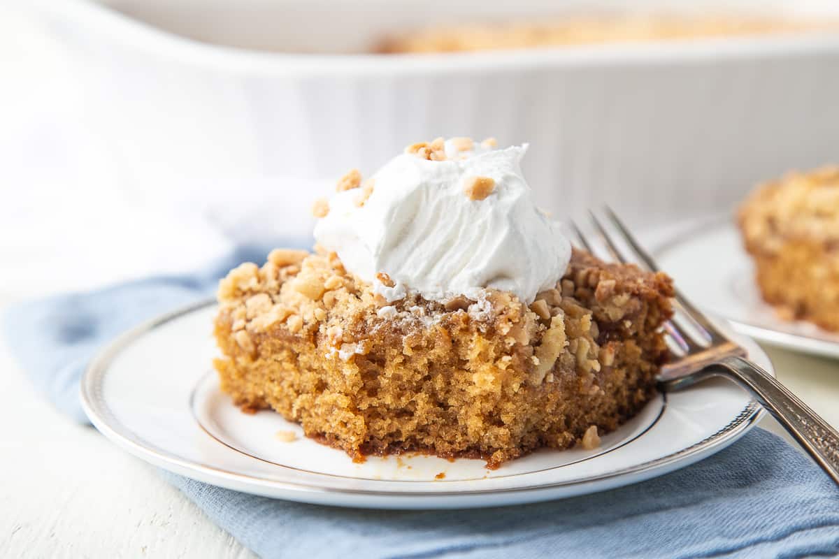 slice of heath bar cake with a bite taken out on a white plate with a fork.