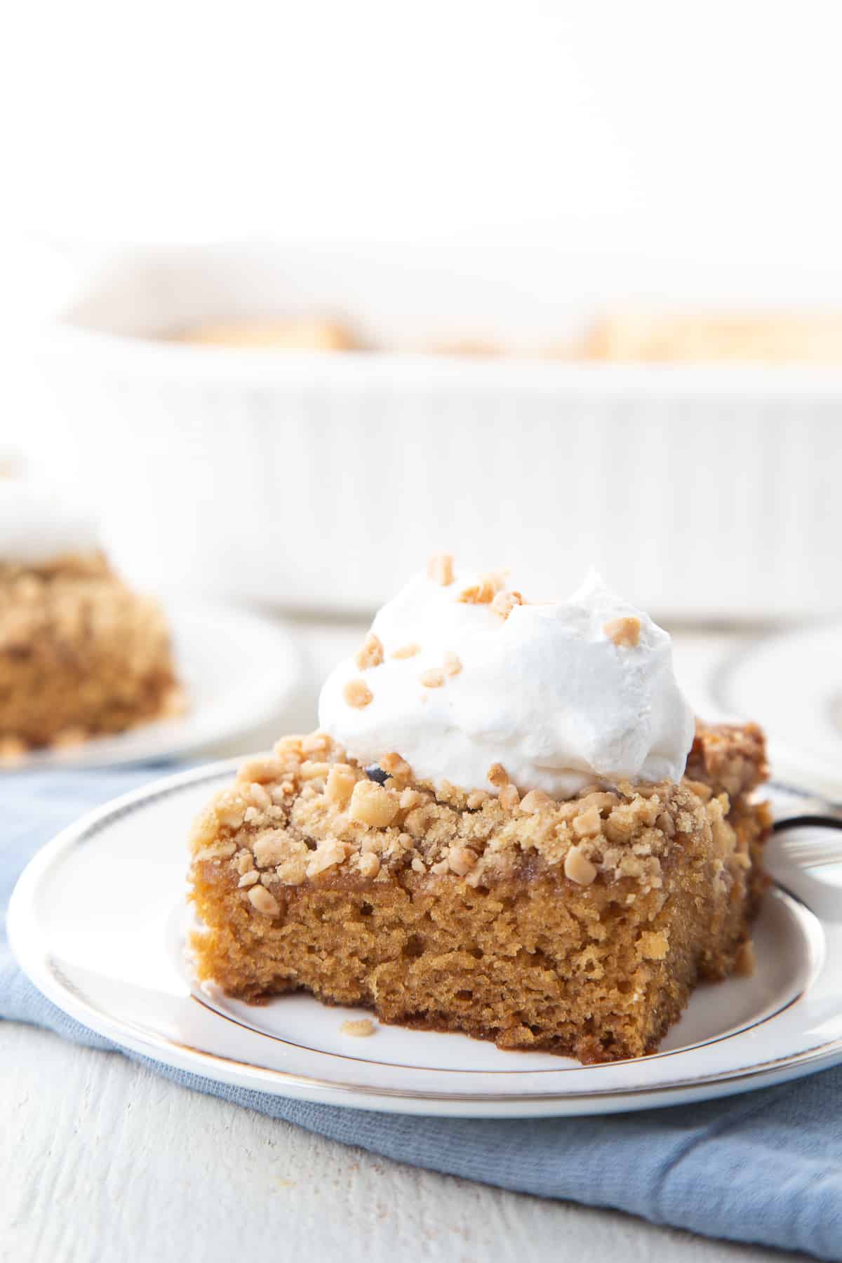 slice of heath bar cake topped with whipped cream on a white plate.