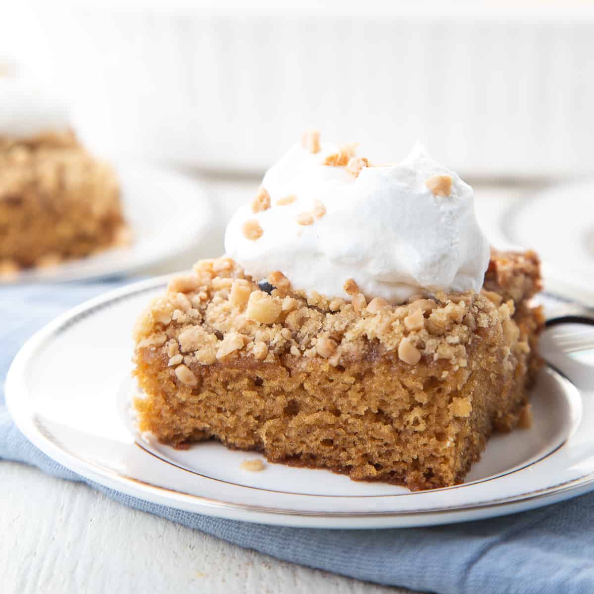 slice of heath bar cake topped with whipped cream on a white plate.