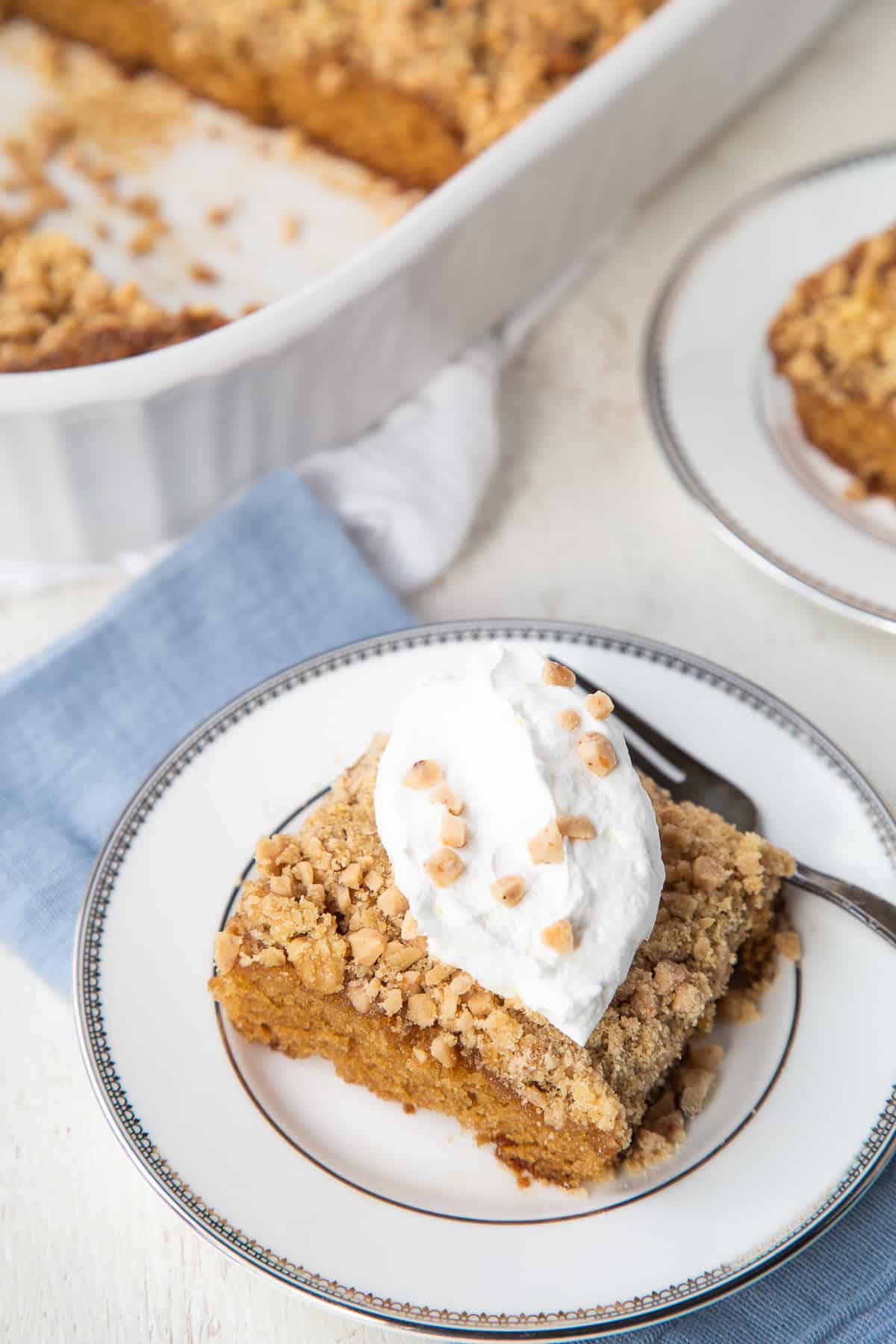 slice of heath bar cake next to a white pan containing the whole cake.