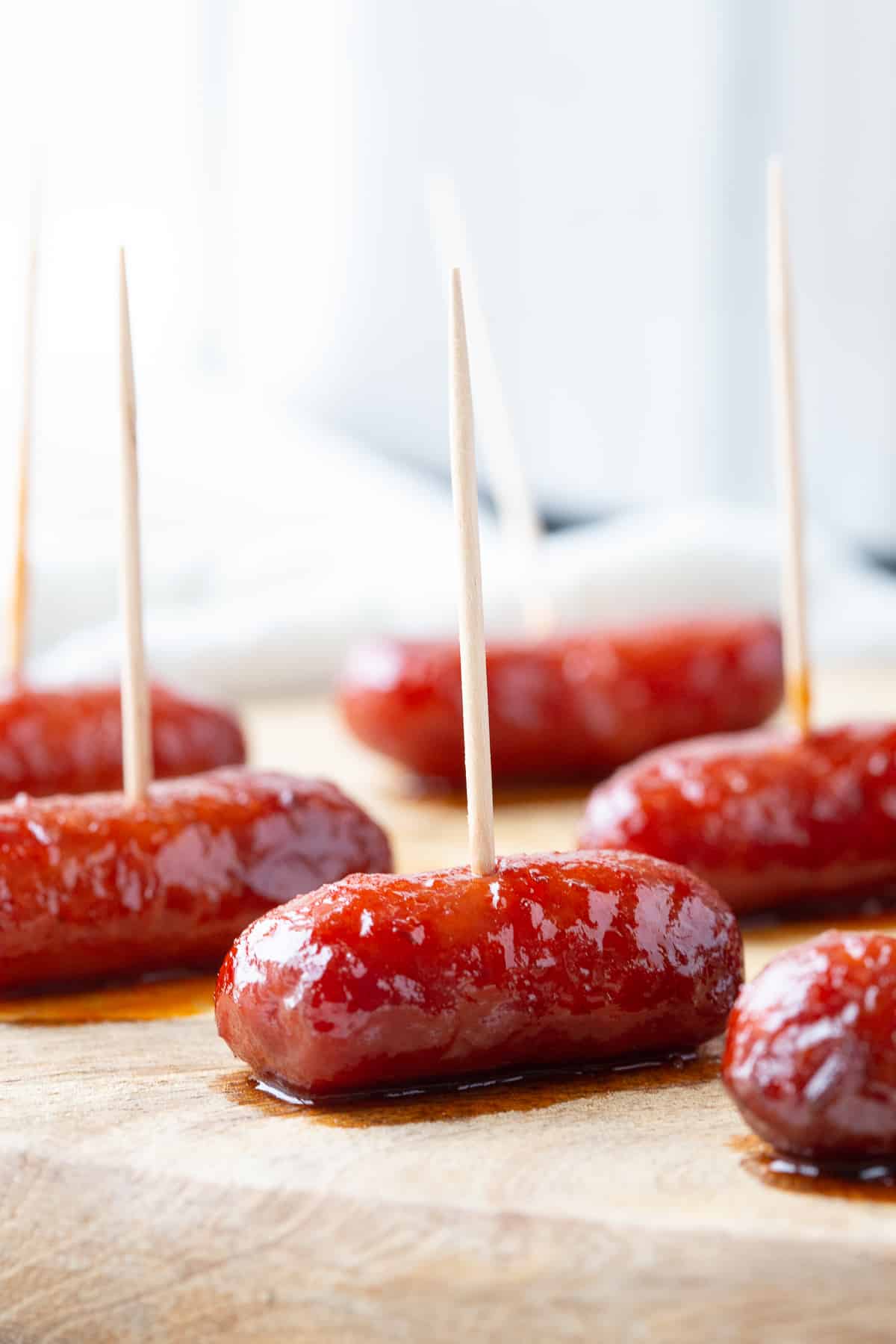 crockpot little smokies on toothpicks on a wooden board.