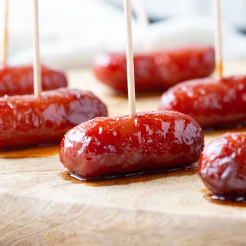 crockpot little smokies with toothpicks on a wooden board.