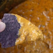 a tortilla dip scooping up queso.