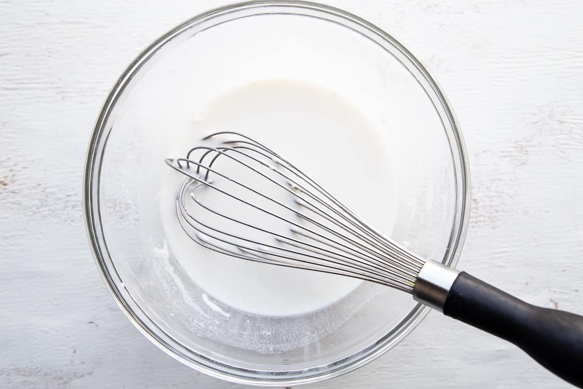 milk and flour in a glass bowl with a whisk.