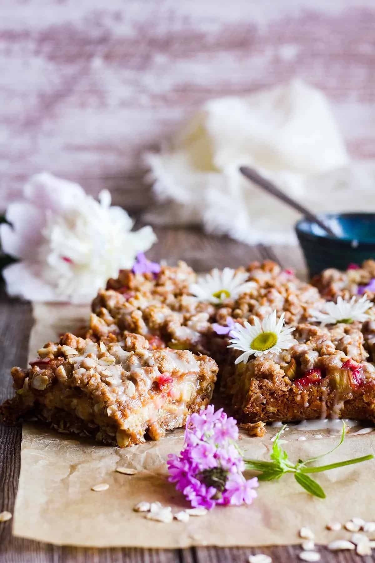 rhubarb oatmeal bars on a piece of parchment paper with edible flowers.