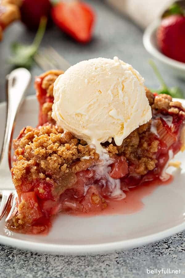 strawberry rhubarb pie slice topped with ice cream.