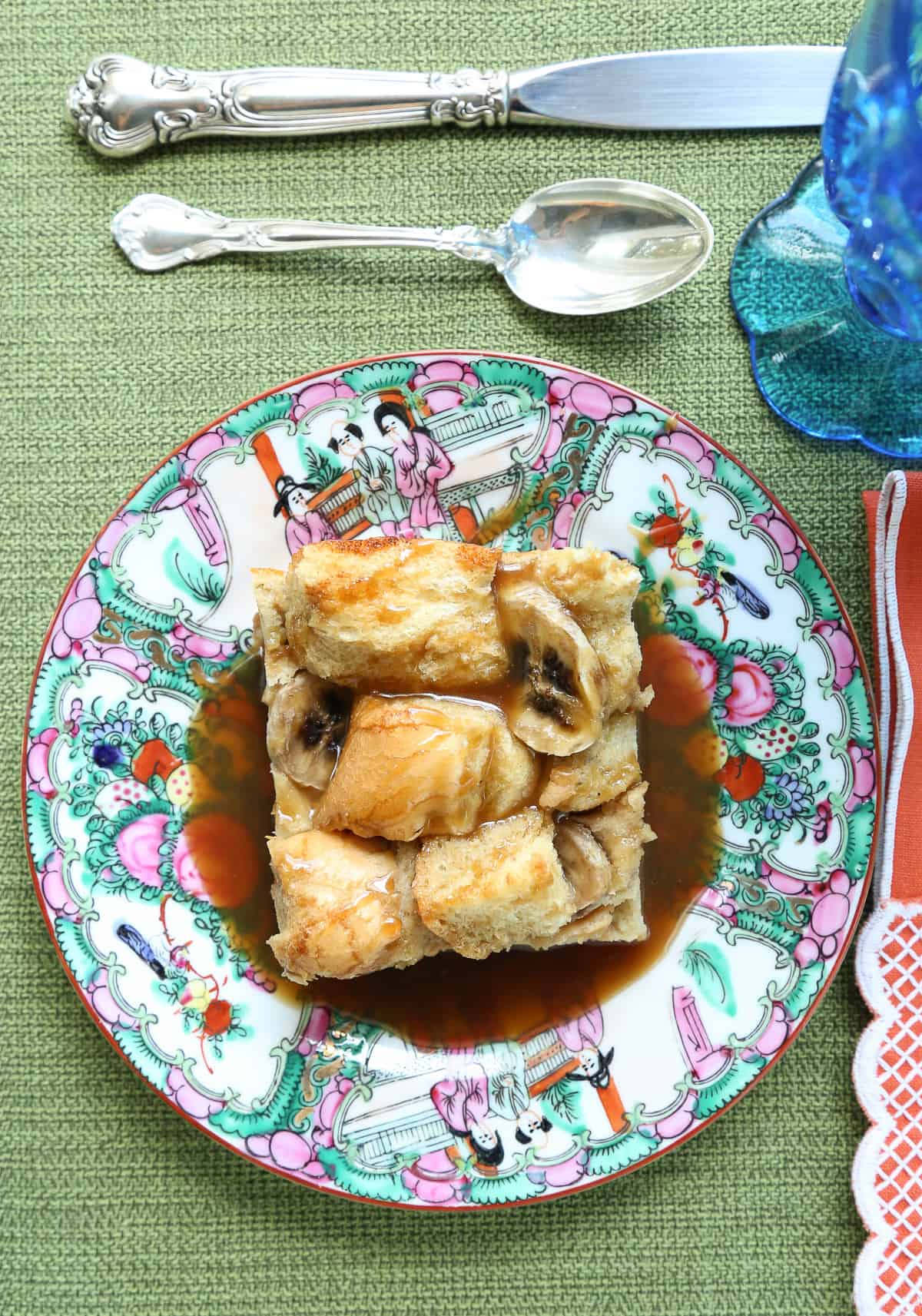 green tablecloth with a colorful piece of china holding banana bread french toast casserole.