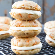 3 carrot cake whoopie pies stacked on a wire rack.