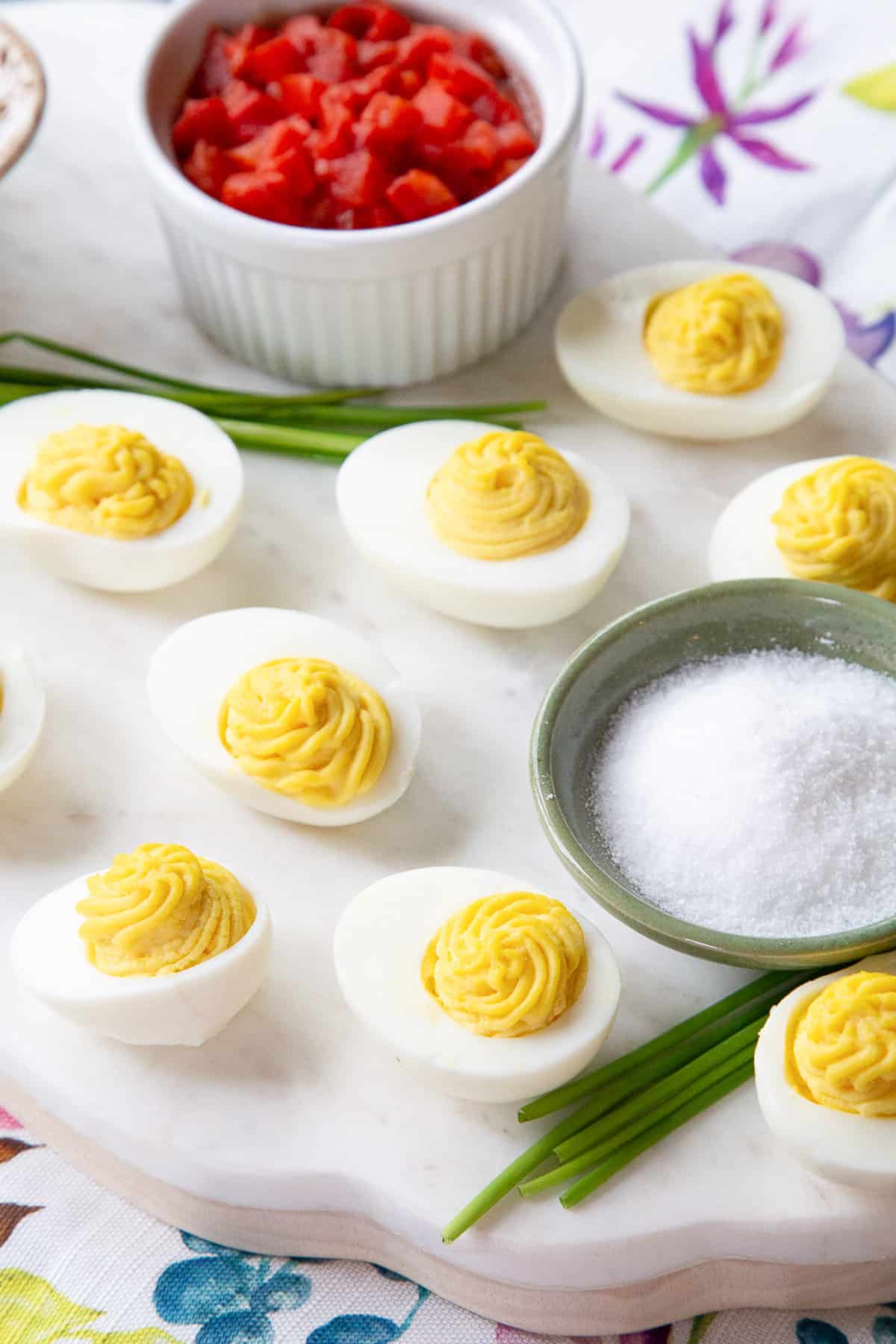 deviled eggs on a white platter with roasted red pepper in a ramekin.