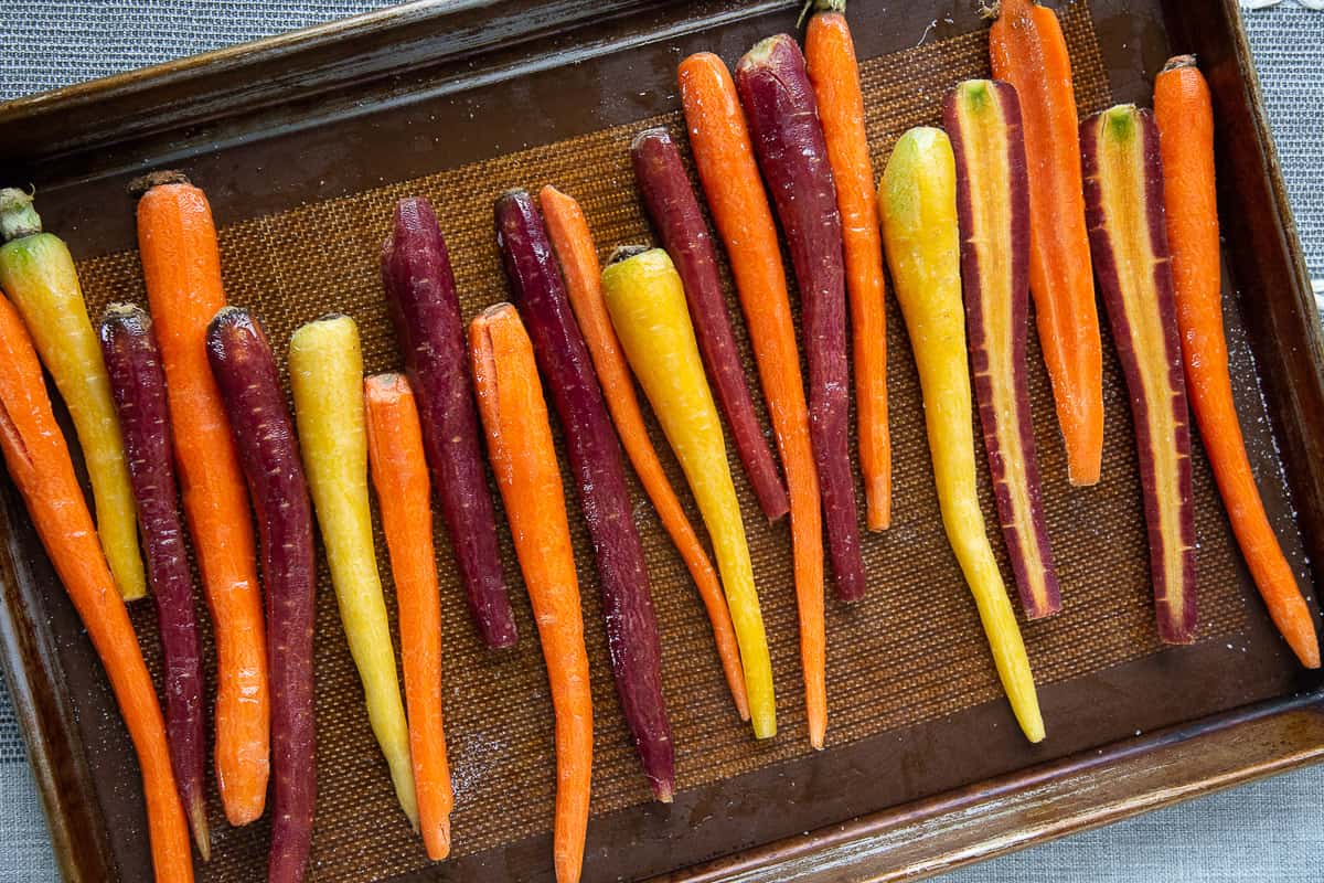 uncooked rainbow carrots on a sheet pan.
