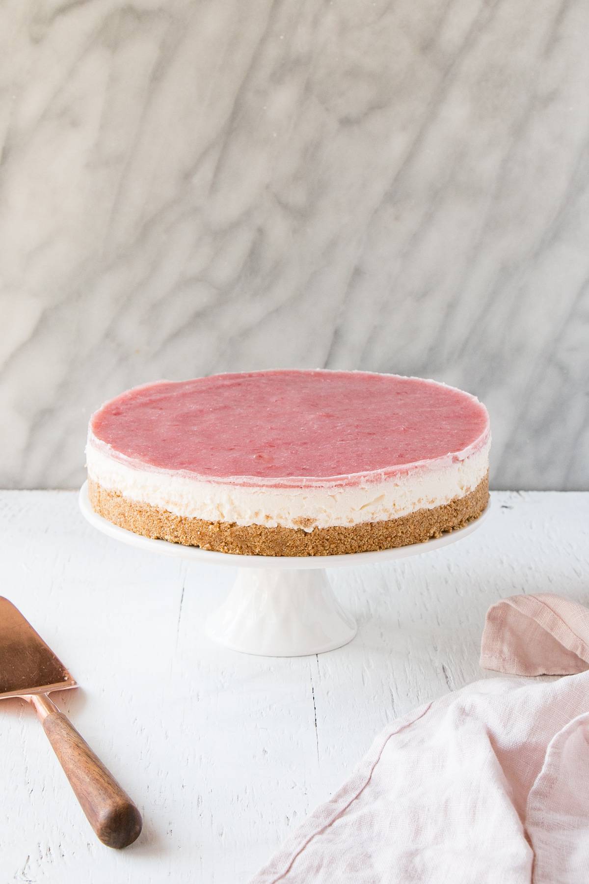 rhubarb cheesecake on a white cake pedestal