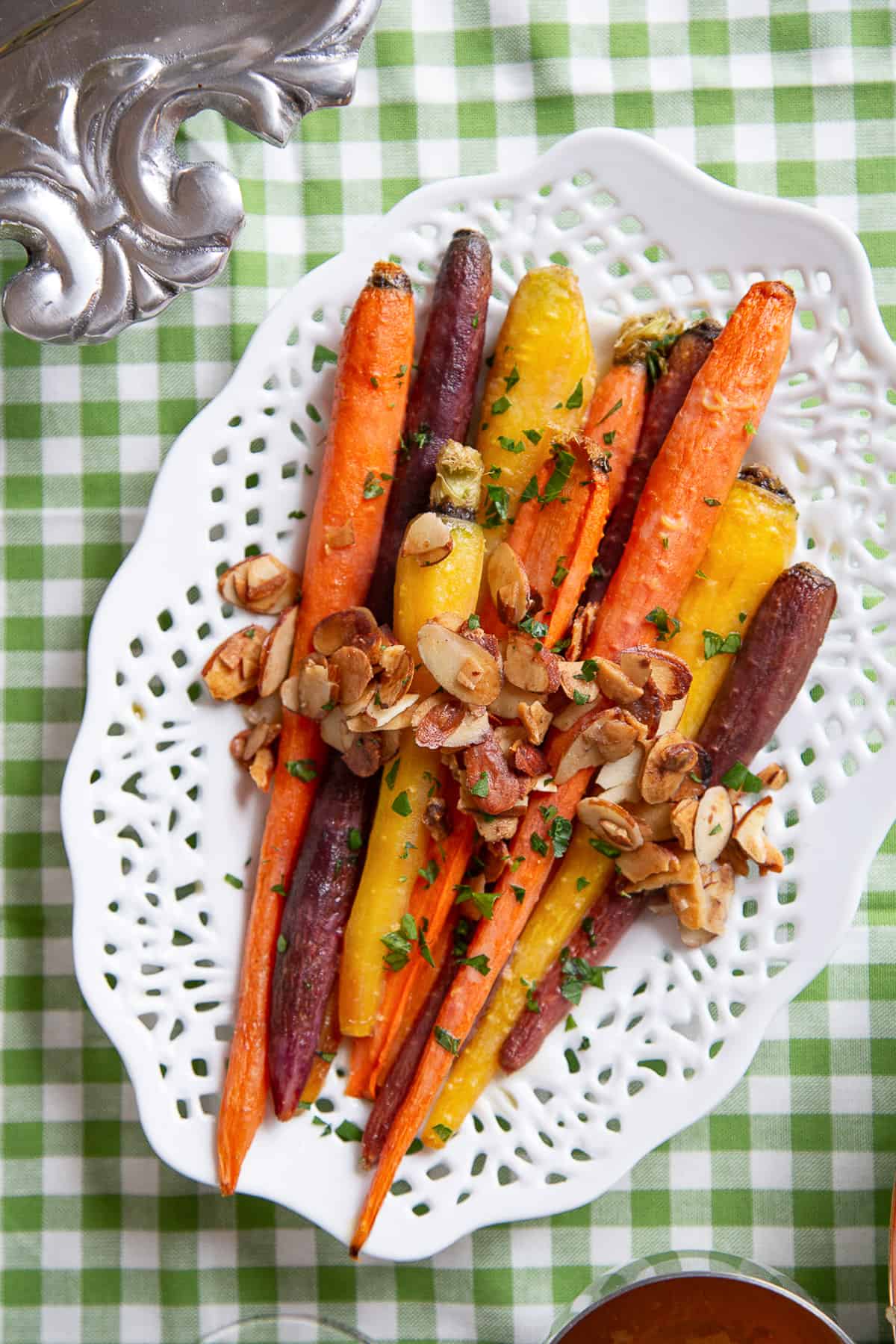 brown sugar glazed carrots on a white platter on a green gingham tablecloth.
