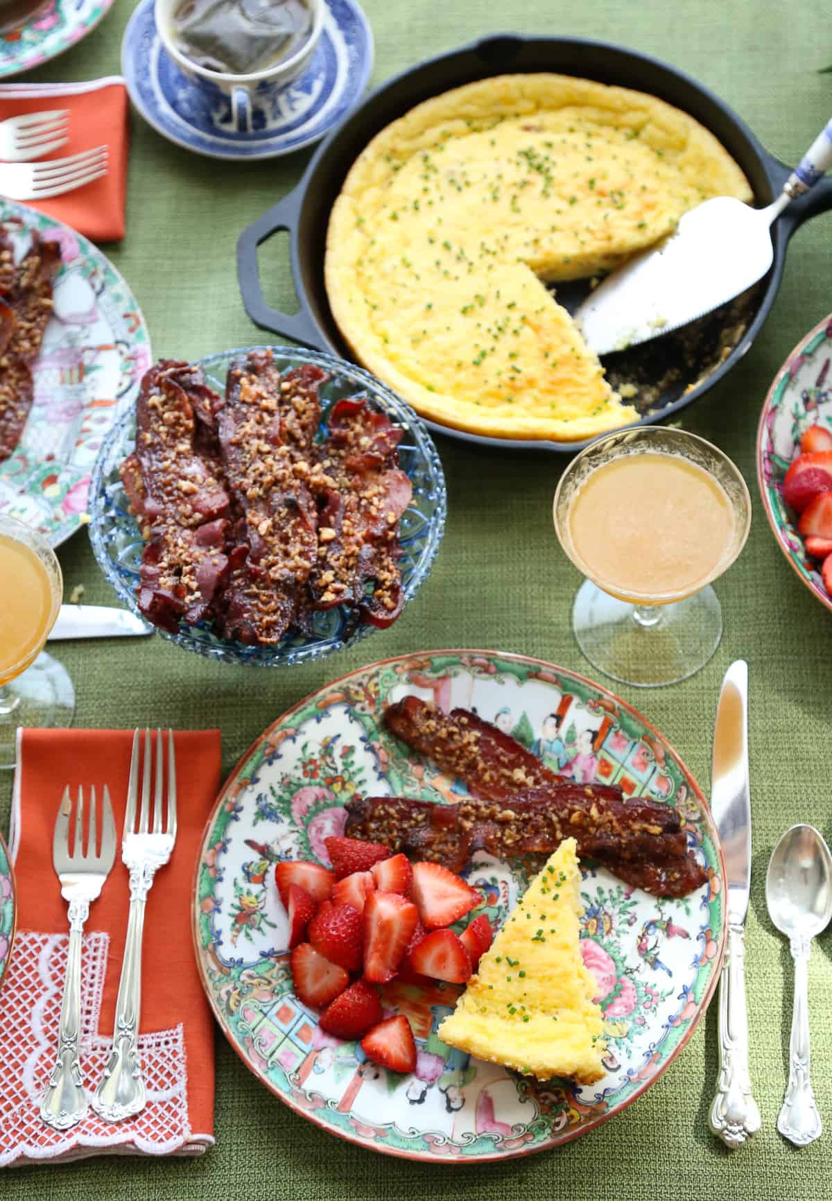 table set with colorful china, orange lace napkins, and brunch food.