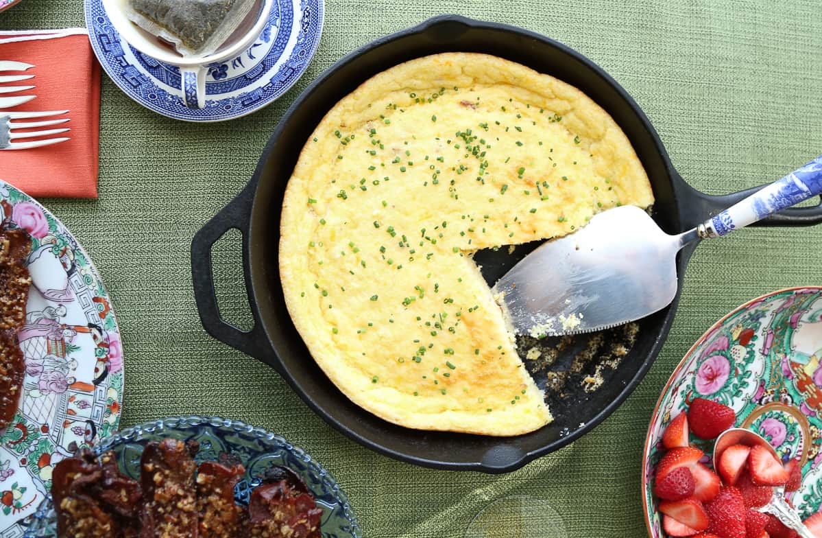 spoon bread in a cast iron skillet with a metal spatula.