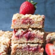 strawberry rhubarb bars stacked with a strawberry on top.