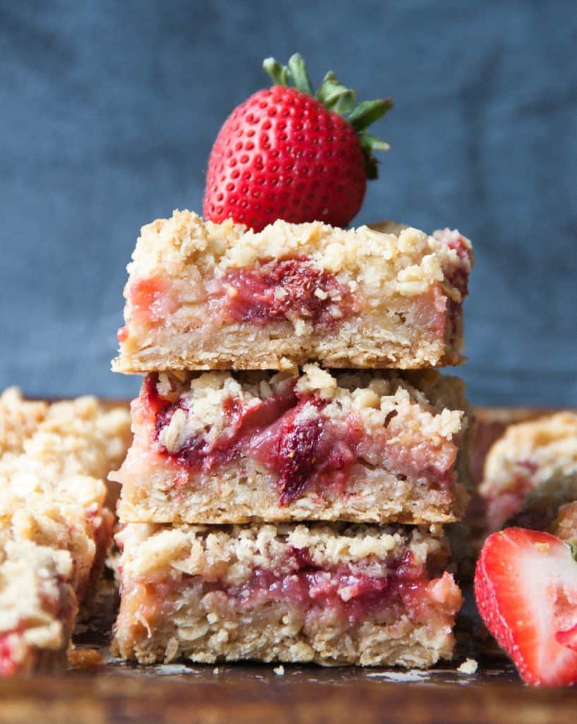 strawberry rhubarb bars stacked with a strawberry on top.