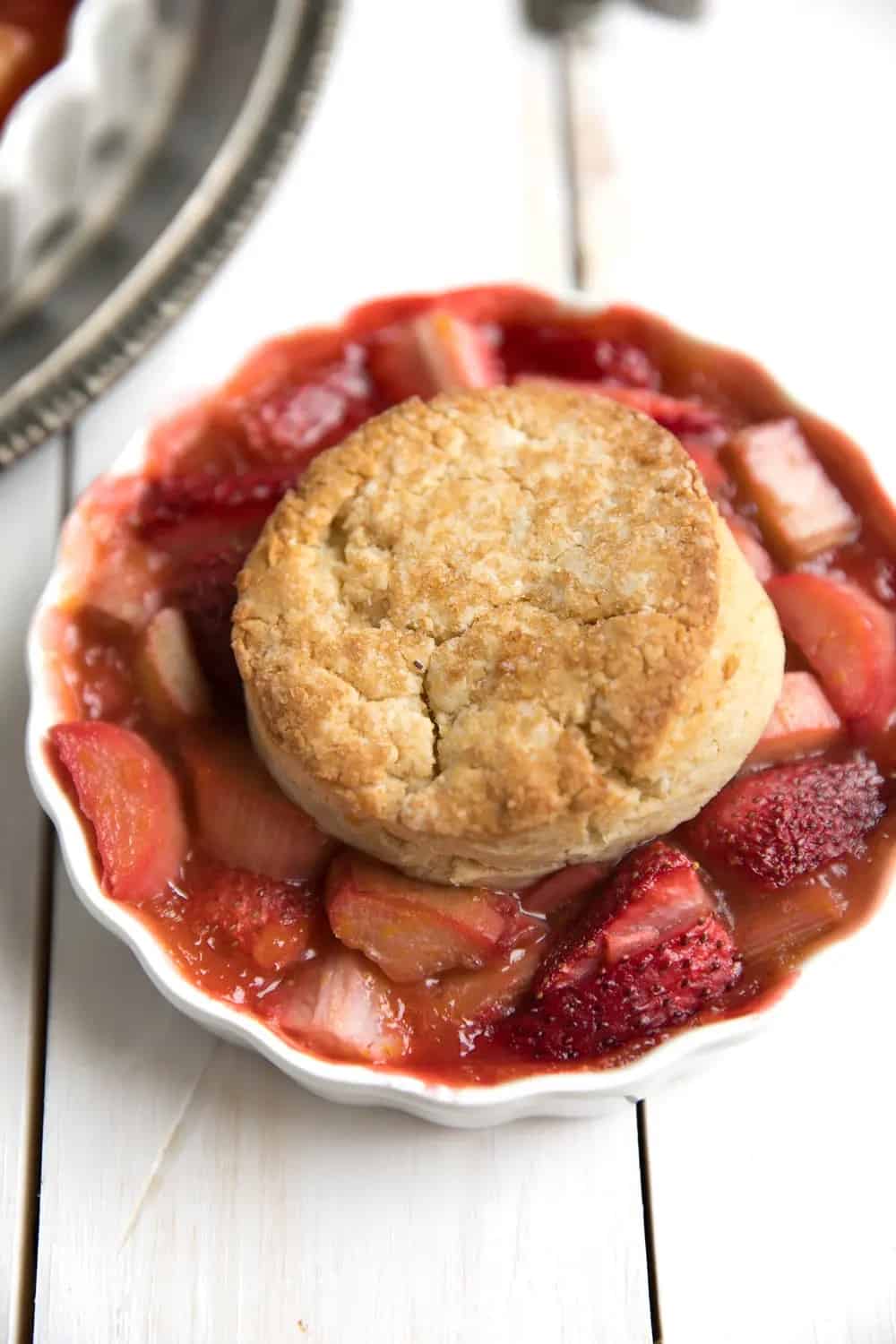 rhubarb cobbler topped with a biscuit in a white dish.