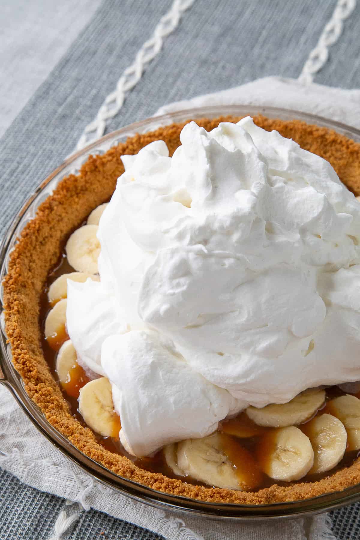 whipped cream piled on top of sliced bananas in a pie.
