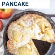 german pancake with apples in a cast iron pan with a slice taken out.