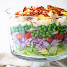 7 layer salad in a glass trifle dish.