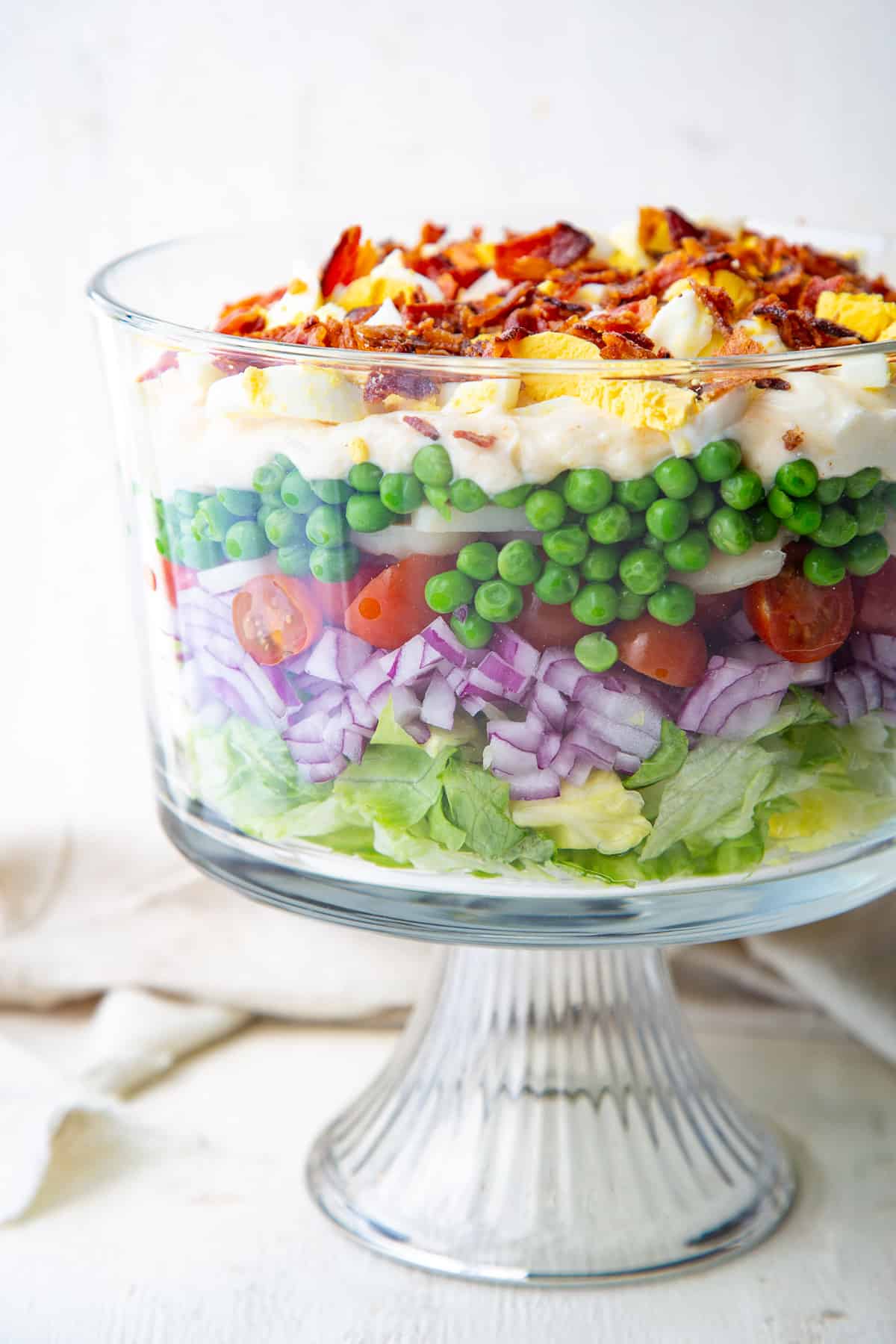 7 layer salad in a glass trifle dish.