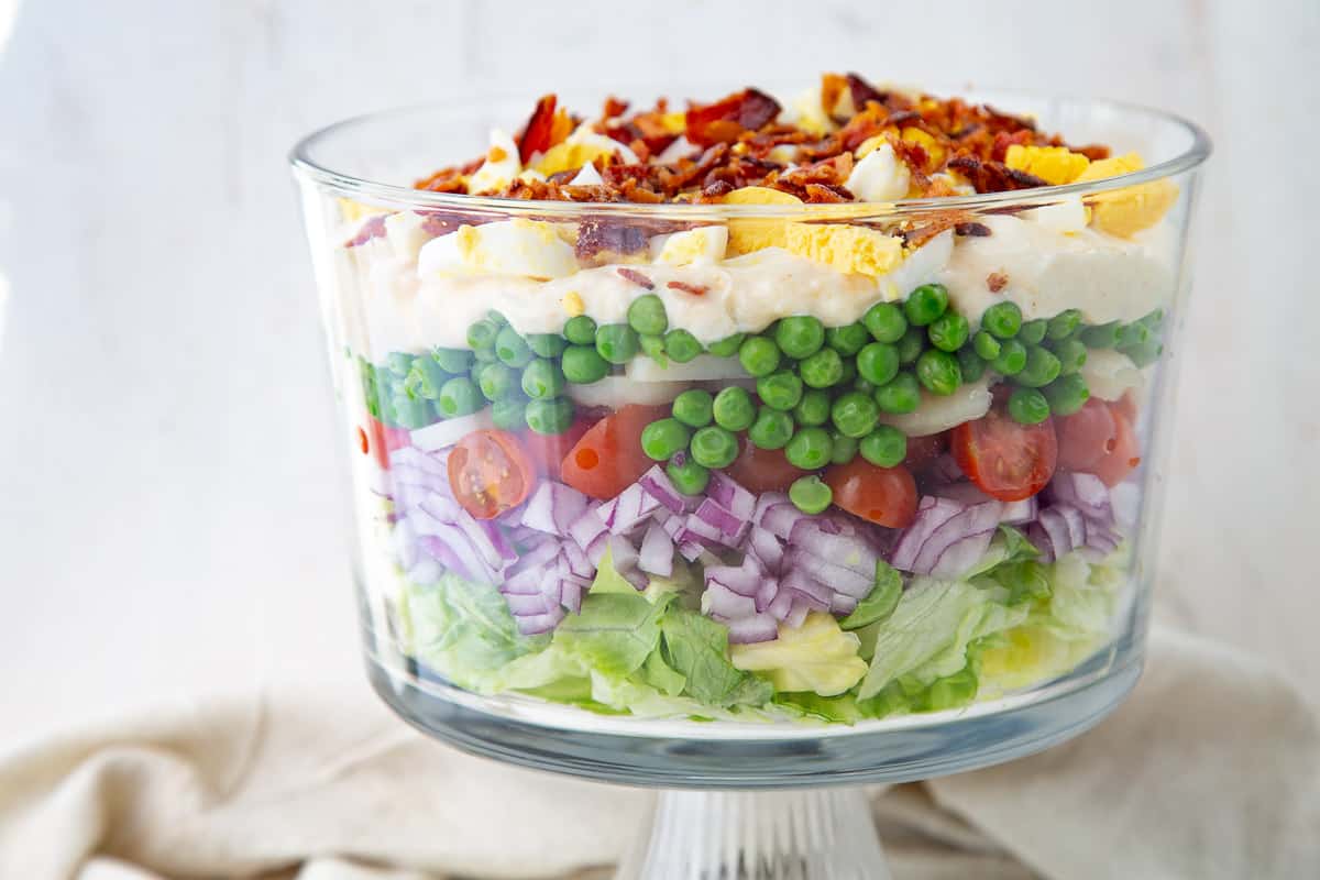 7 layer salad in a glass trifle dish.