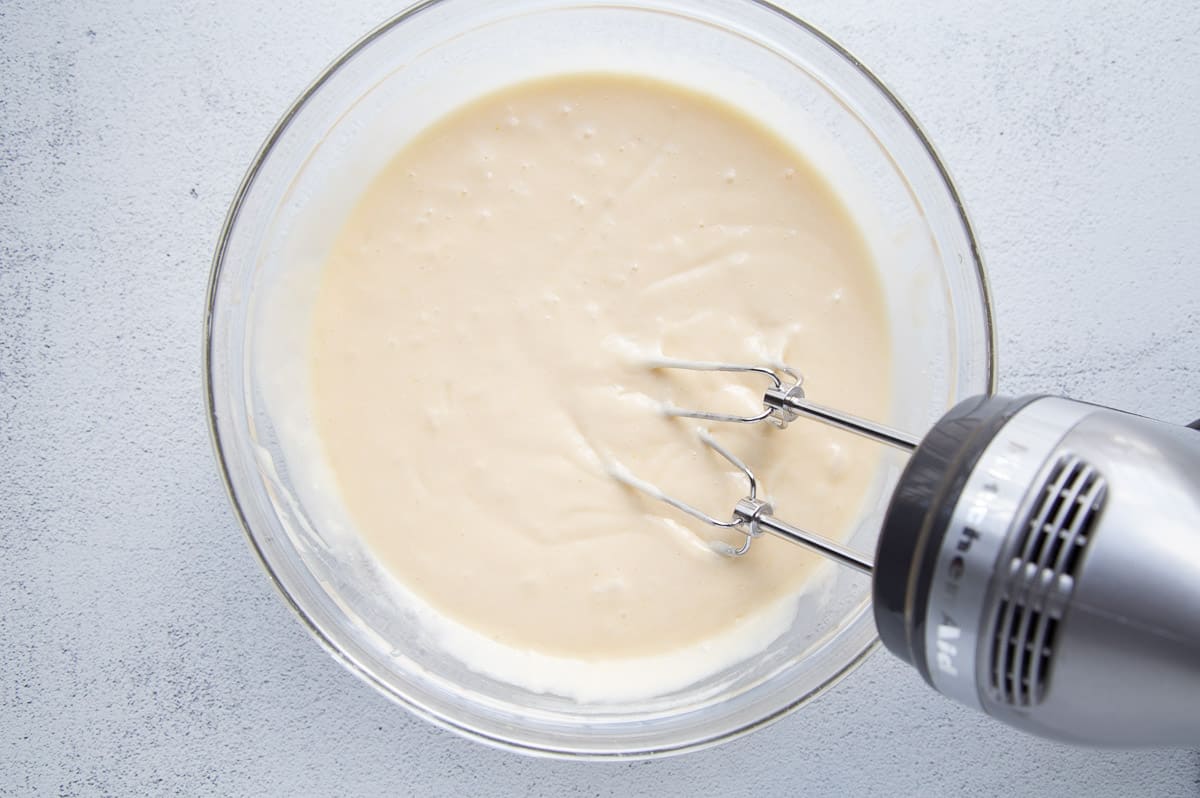 cake batter in a glass bowl with a hand mixer.