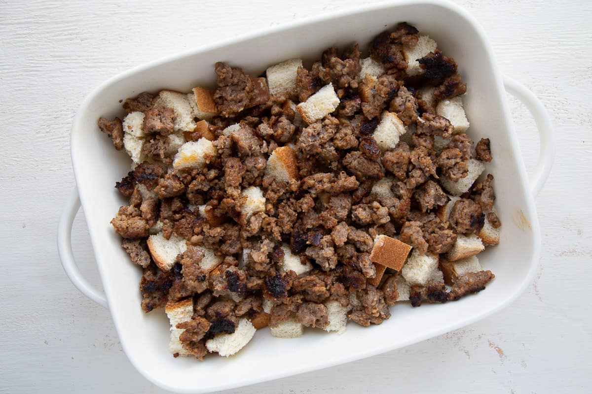 sausage and cubed bread in a white dish.