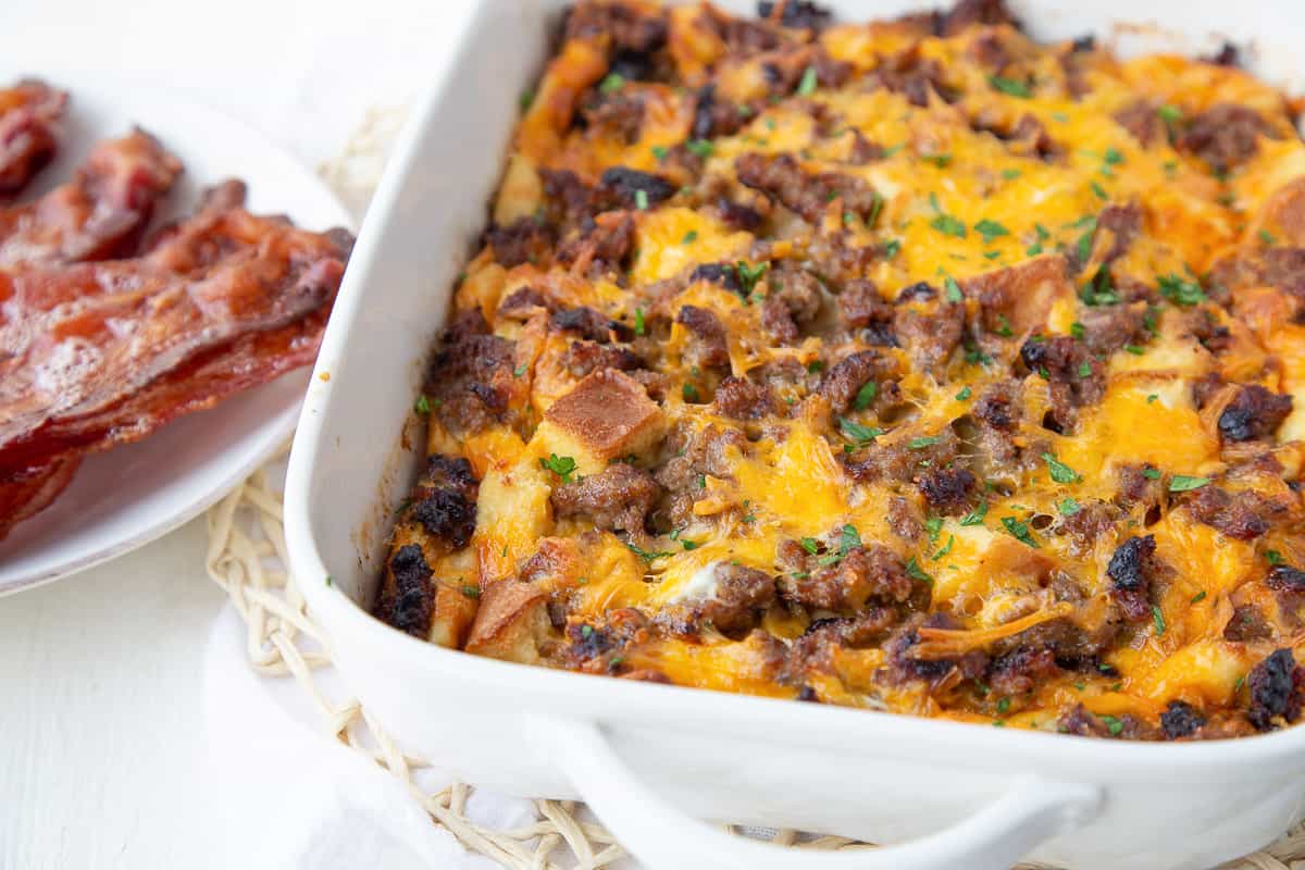 egg casserole next to a plate of bacon.