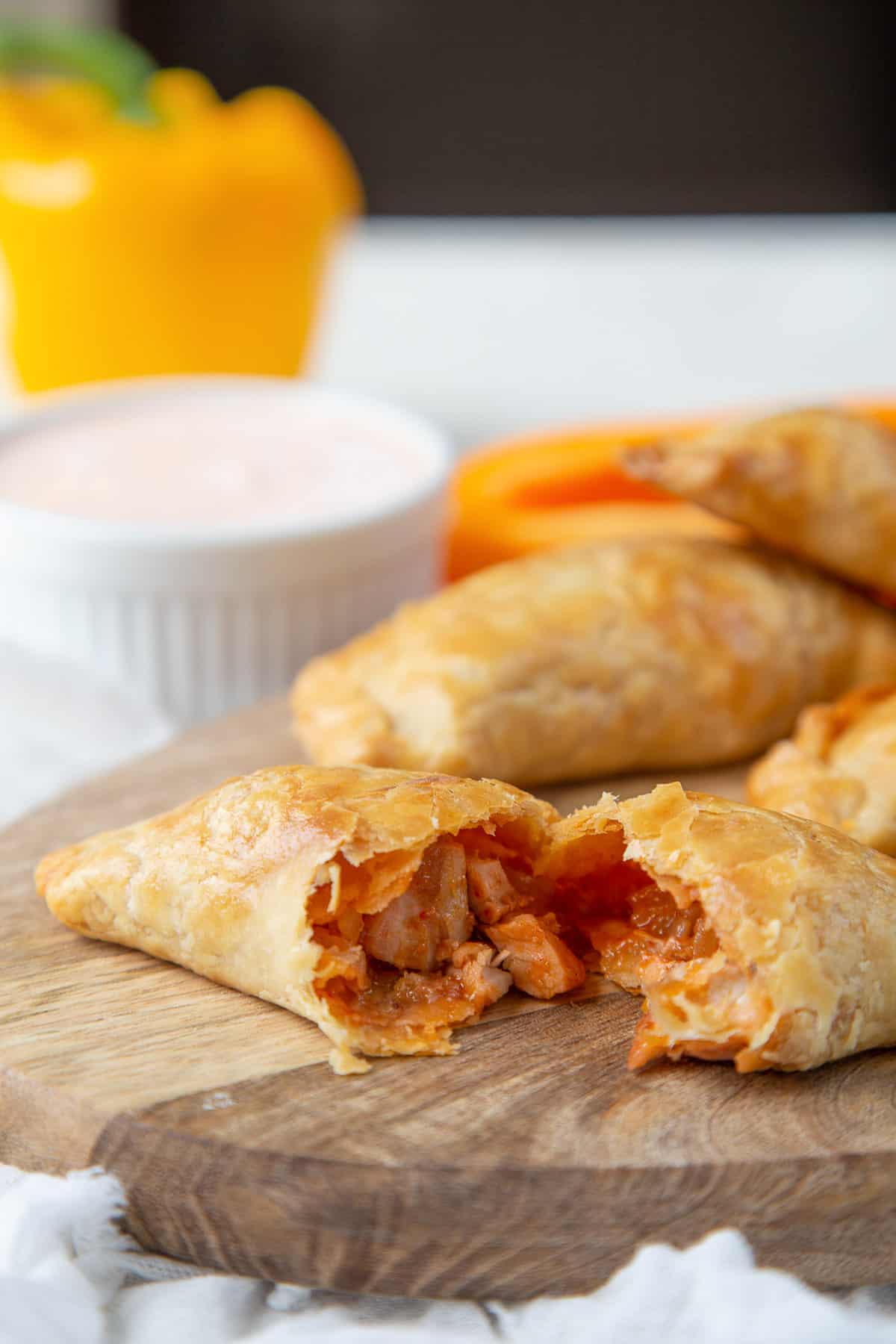 baked empanada with chicken on a wooden cutting board.