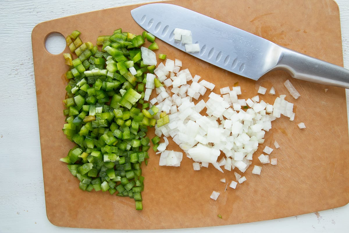 chopped green pepper and onion on a cutting board.