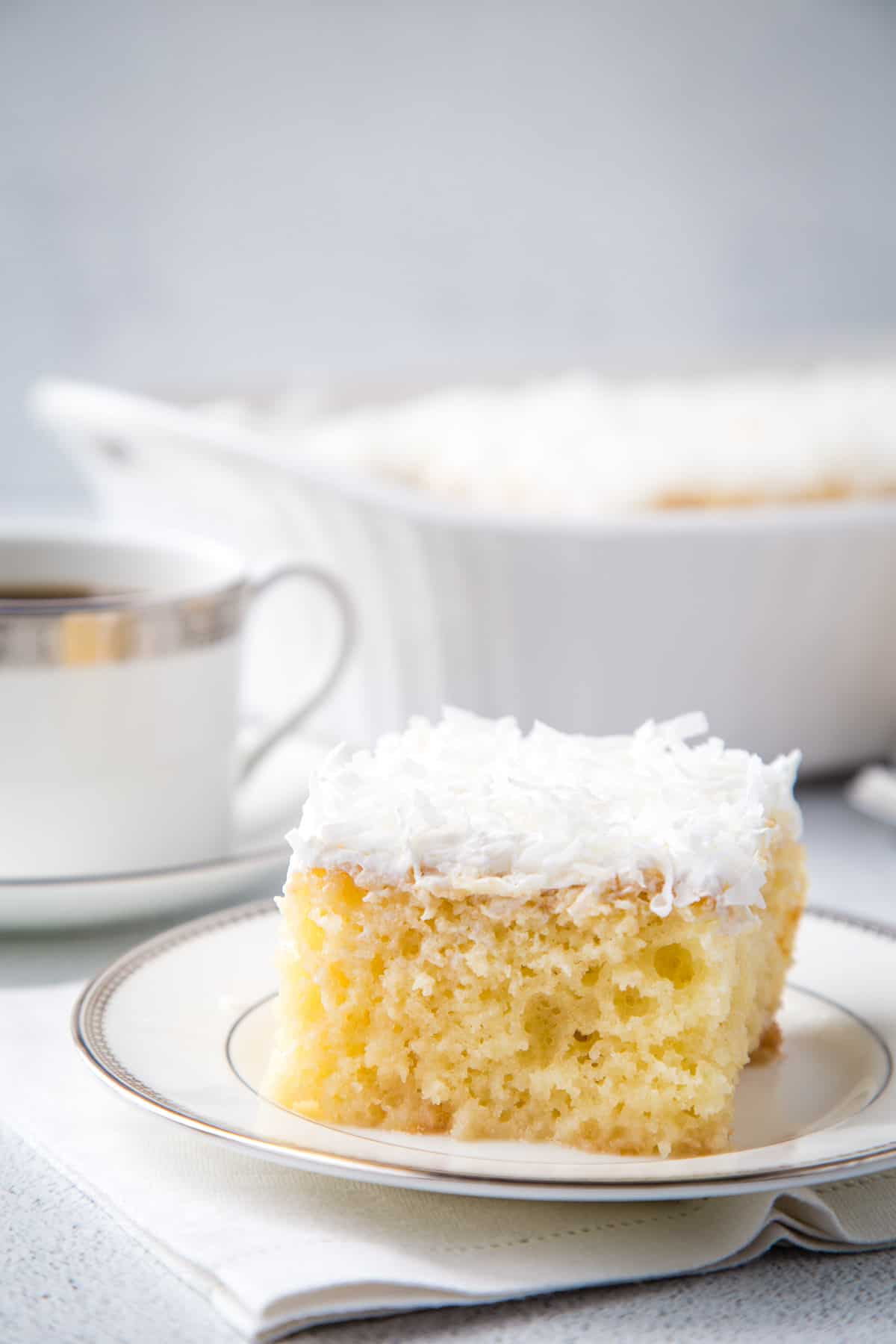 slice of yellow cake topped with whipped cream and coconut.