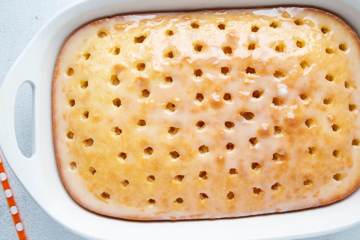 white cake with holes poked in it, with a shiny glaze on top.