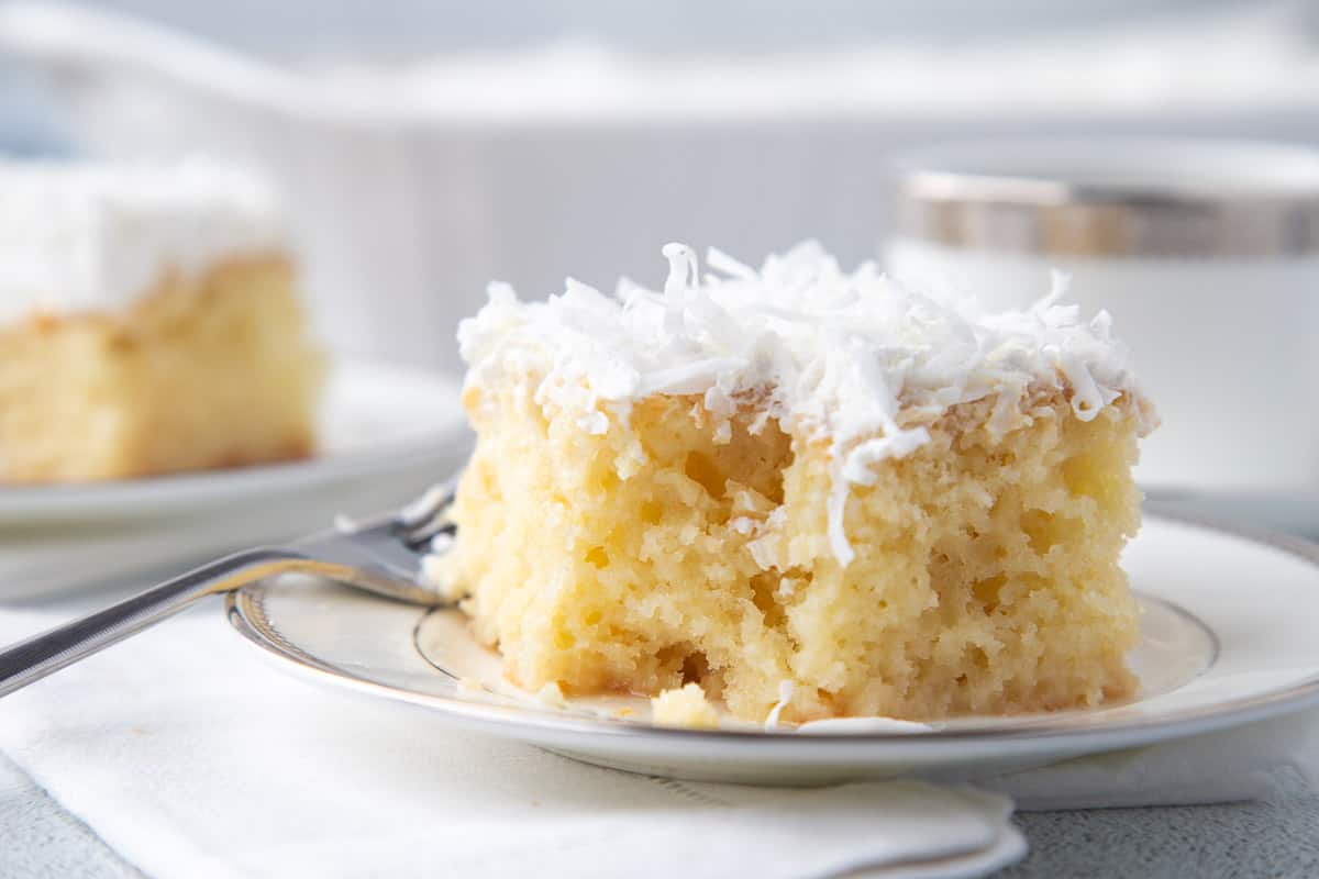 slice of coconut poke cake with a bite taken out.