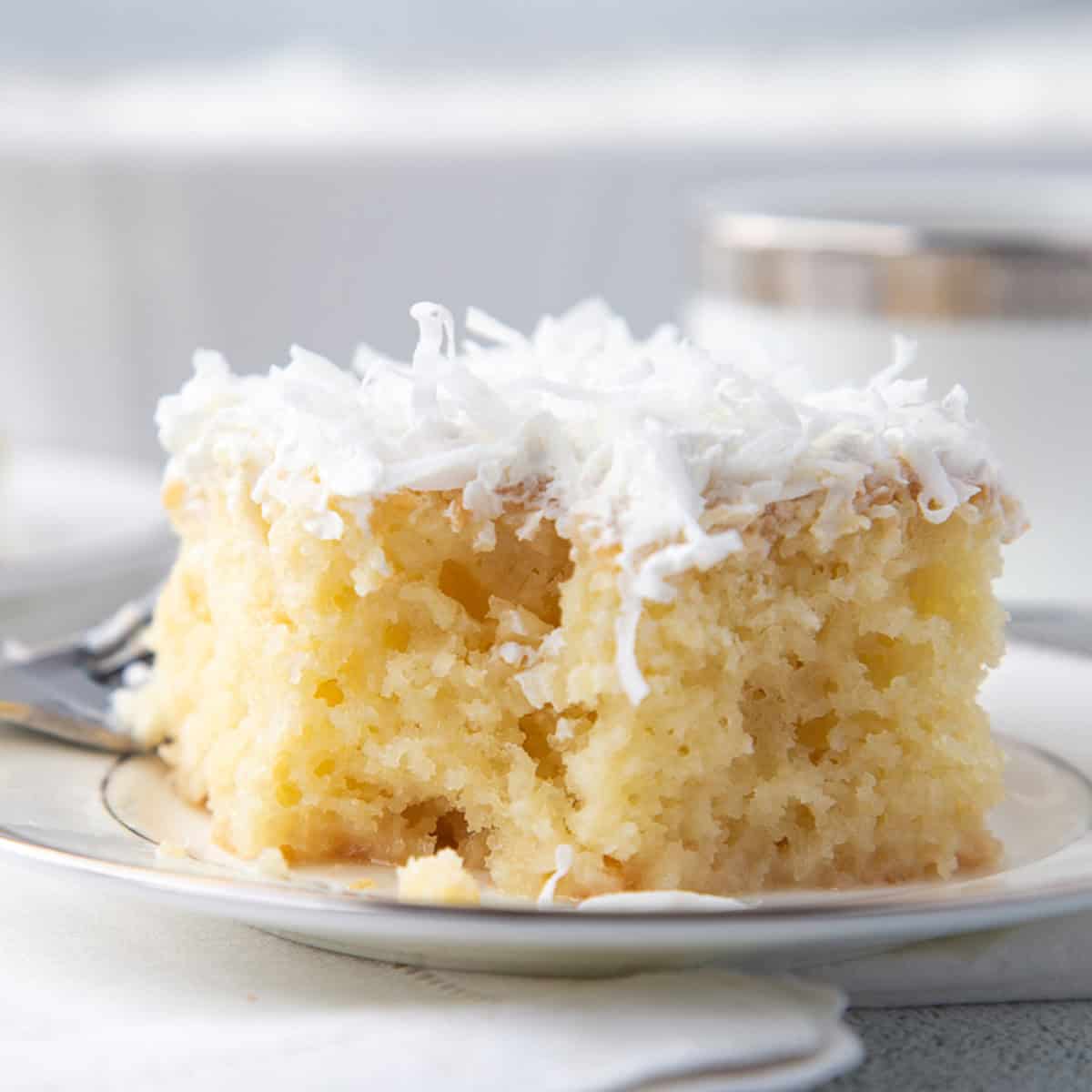 slice of coconut poke cake on a white plate.