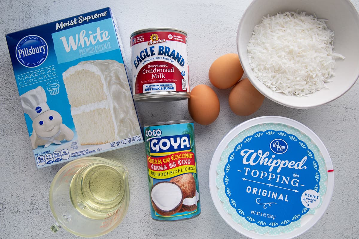 cake mix, cream of coconut, whipped topping, and eggs on a white table.