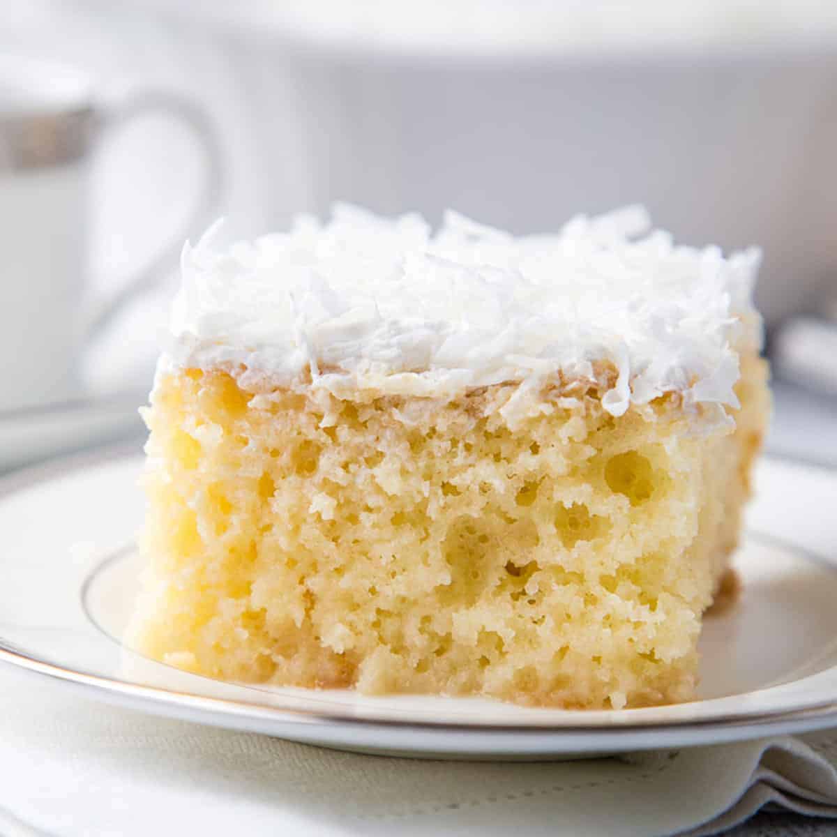 coconut poke cake slice on a white plate.