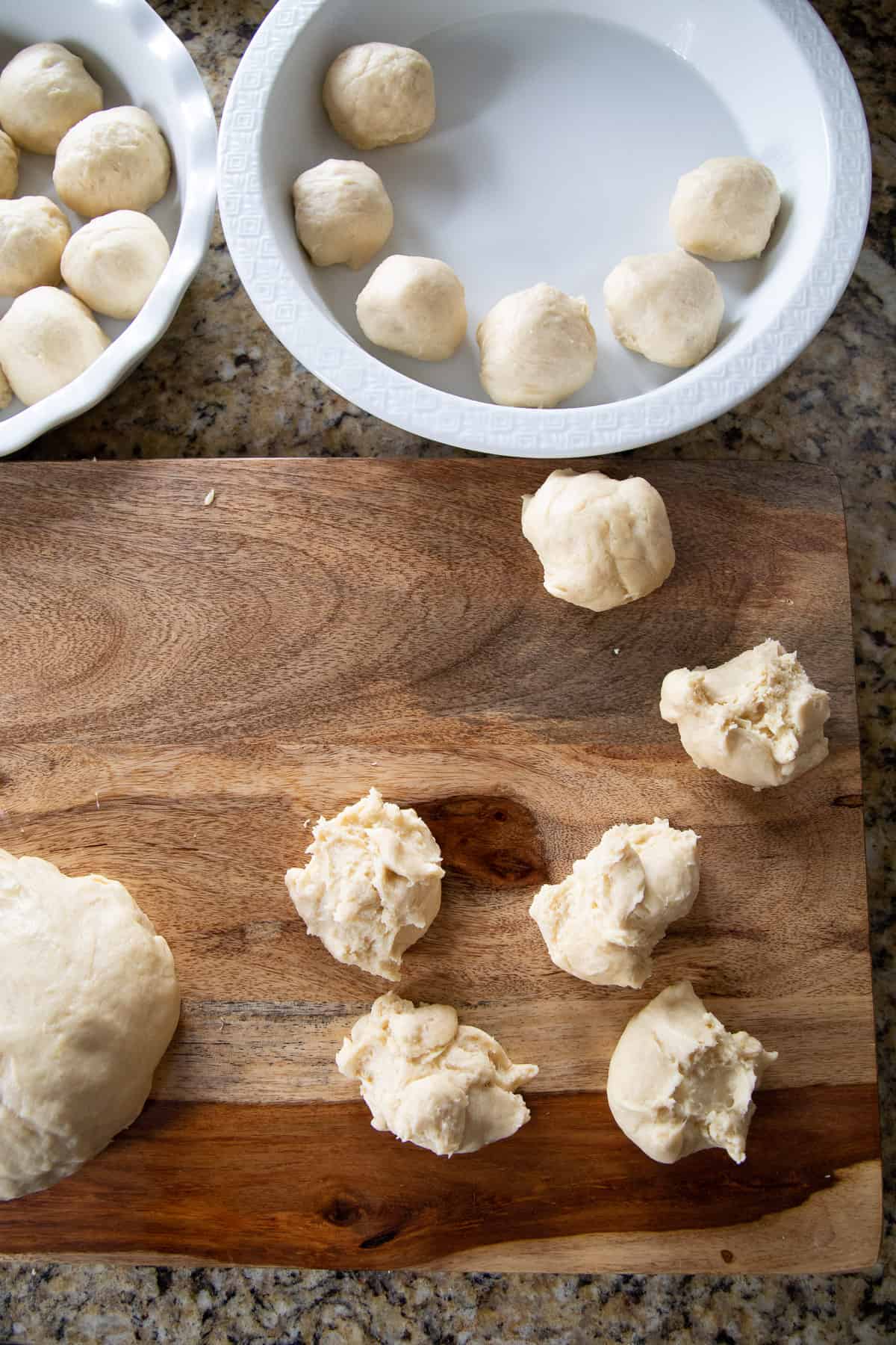 balls of bread dough on a cutting board and in cake pans. 