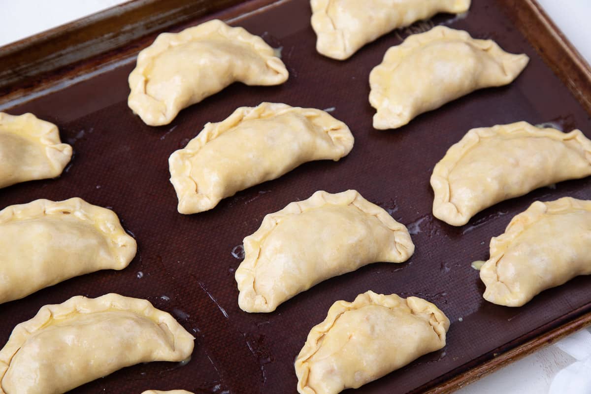 unbaked empanadas on a sheet pan.