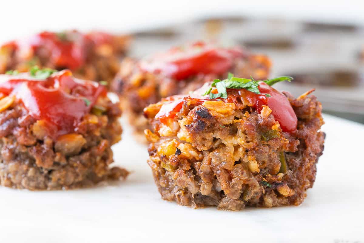 mini meatloaves topped with ketchup on a white platter.