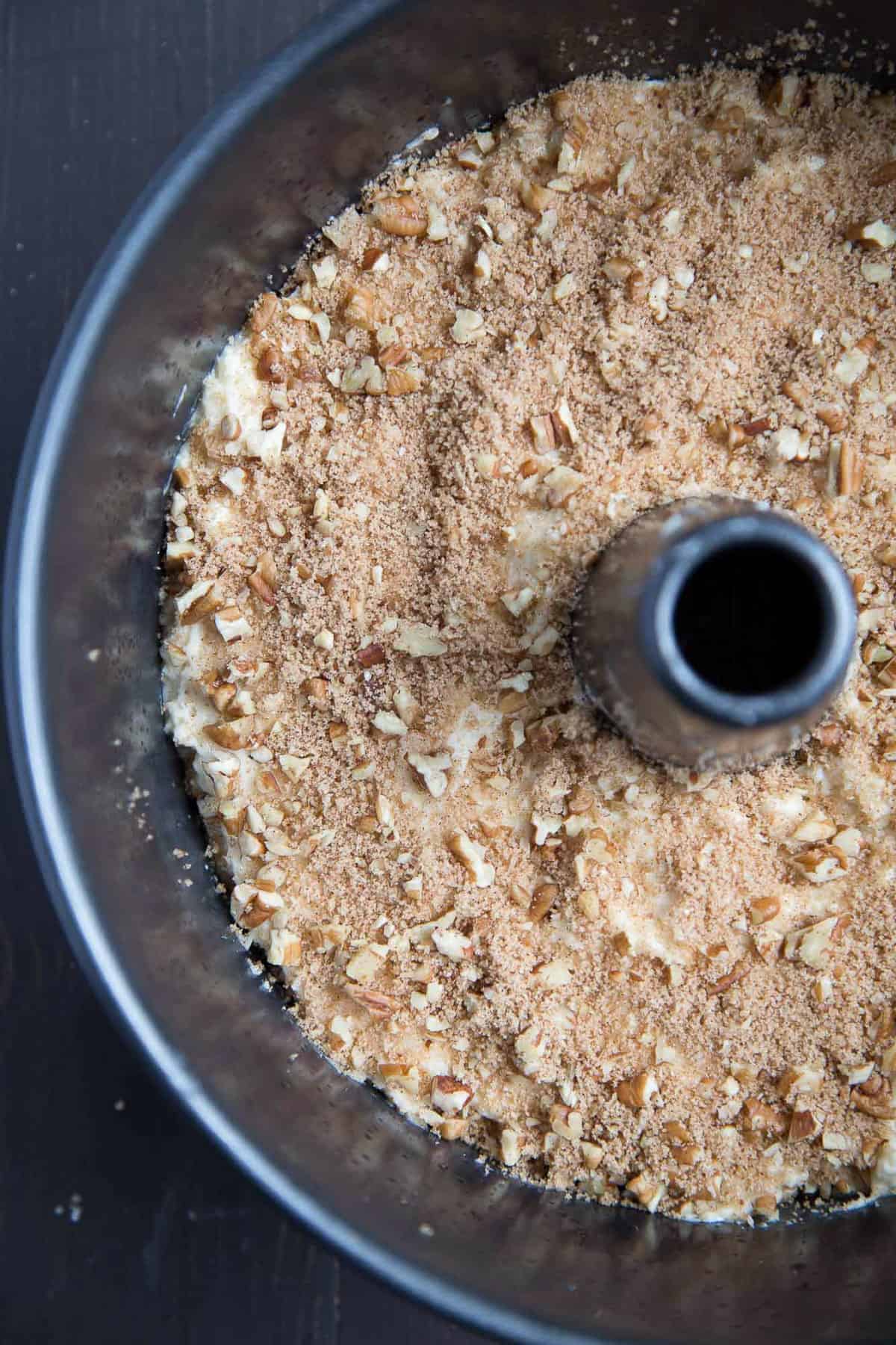 uncooked coffee cake topped with pecans in an angel food cake pan.