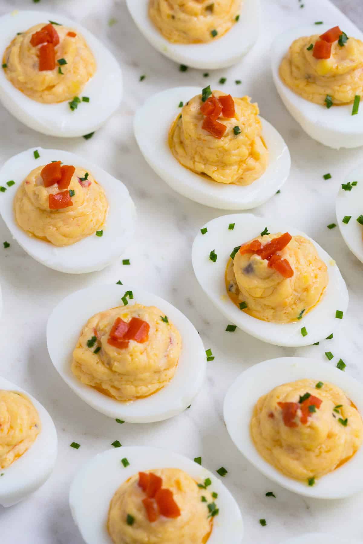 pimento cheese deviled eggs topped with chives.