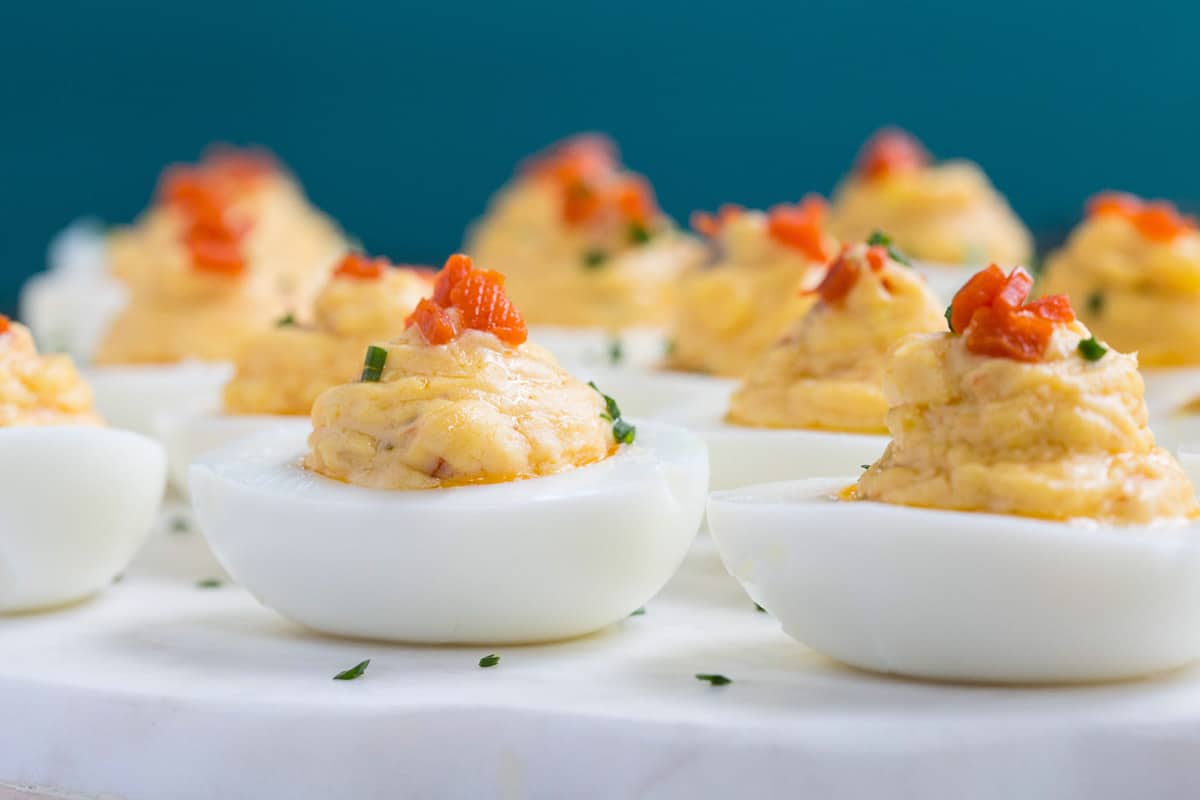 pimento cheese deviled eggs on a white platter.