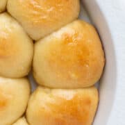 homemade potato rolls in a round white dish.
