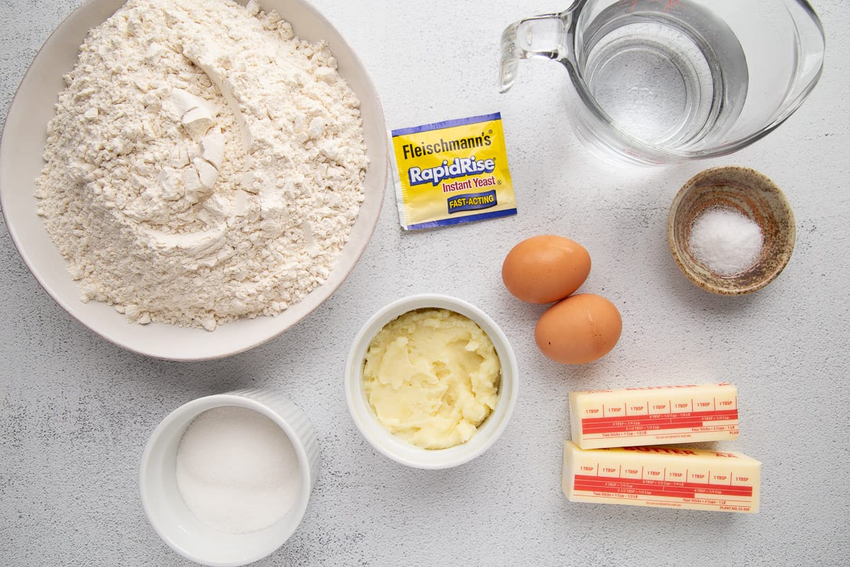 flour, mashed potatoes, butter, eggs, and other ingredients on a white table.