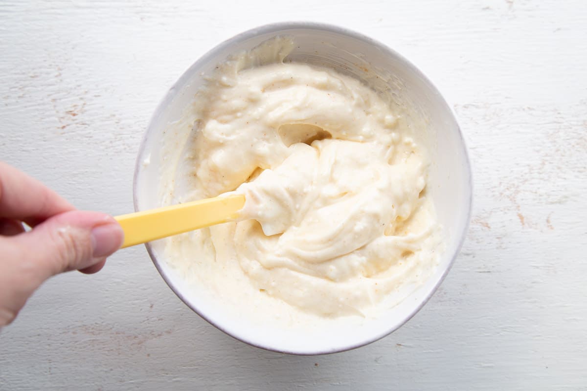 hand stirring mayonnaise dressing with a spatula.