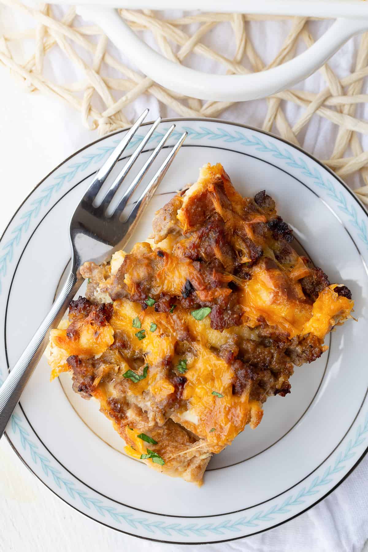 slice of sausage and egg casserole on a white and blue plate.